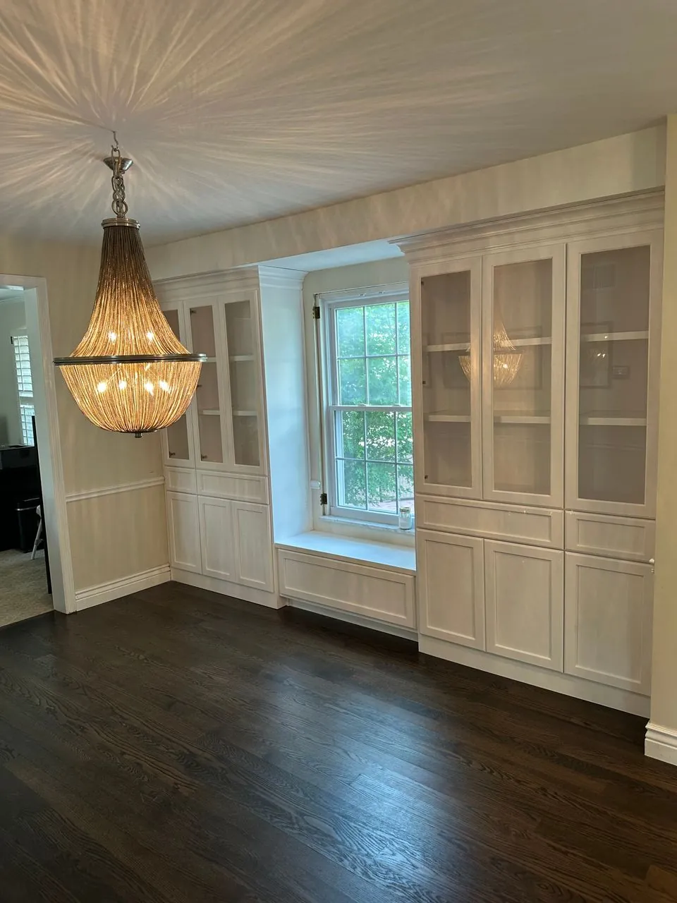Floor-to-ceiling white glass-front built-ins framing a custom window seat in a dining room