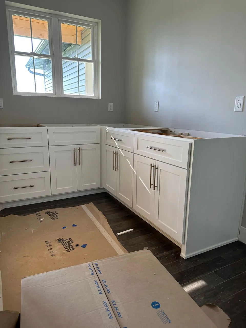 Fitted white Shaker base cabinetry wrapping a bright corner workspace during installation